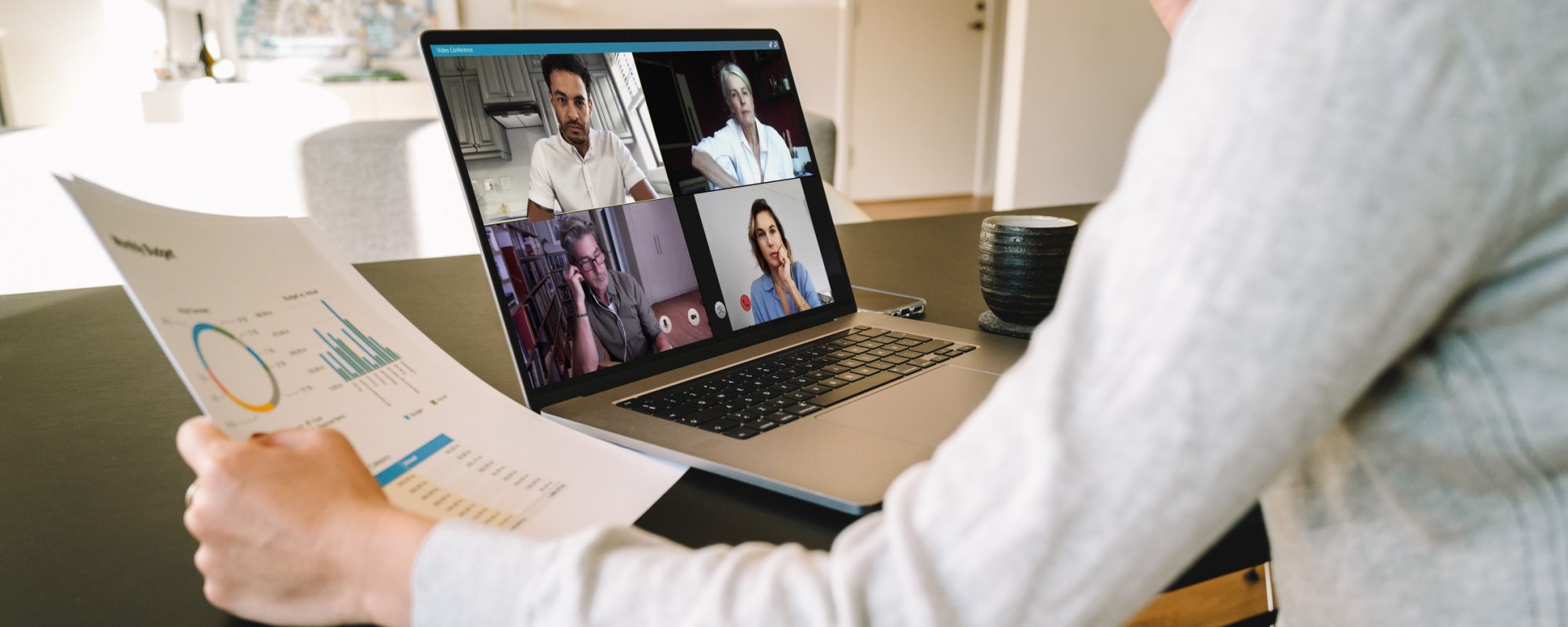 Group of businessmen and businesswomen smart working from home. View from side of woman talking to her colleagues about business plan over a video conference.