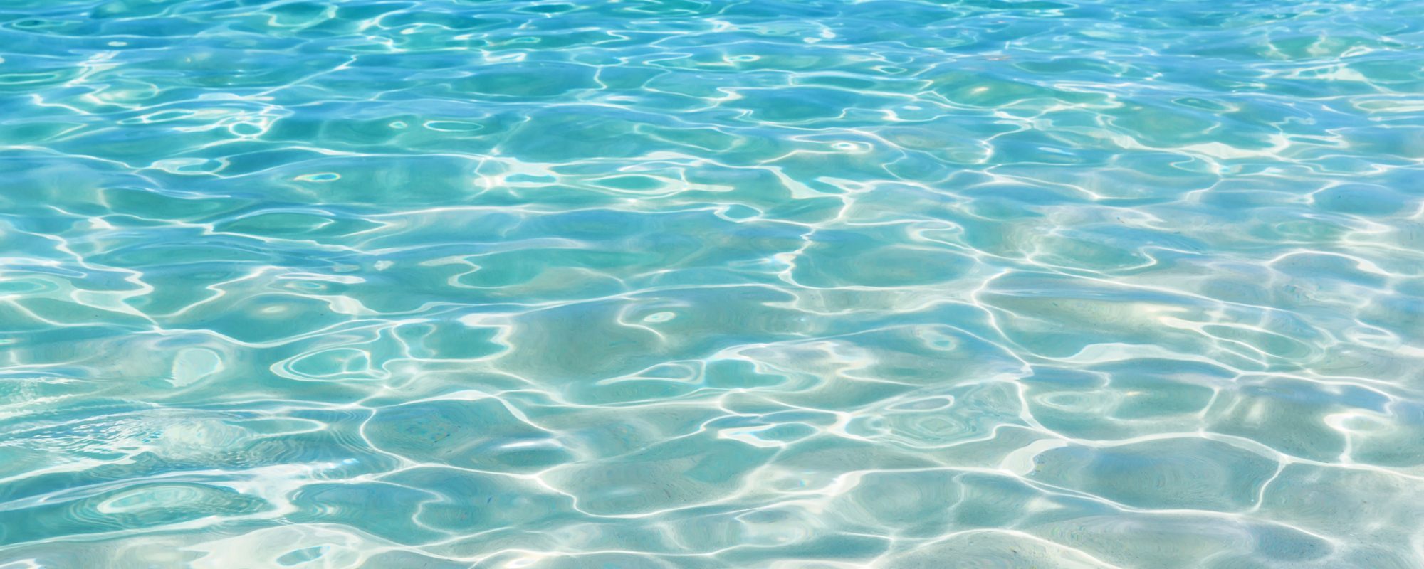 Shining blue water ripple background. Surface of water in swimming pool.
