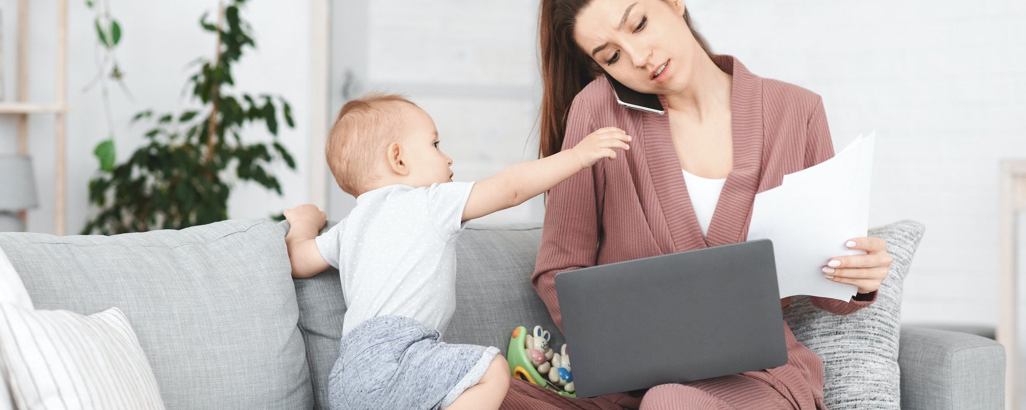 Business And Maternity. Annoyed mom trying to work while toddler distracting her